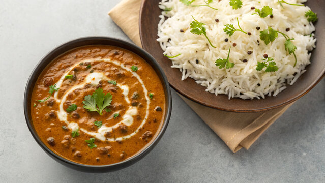 A bowl of creamy dal makhani sits next to a plate of jeera rice.