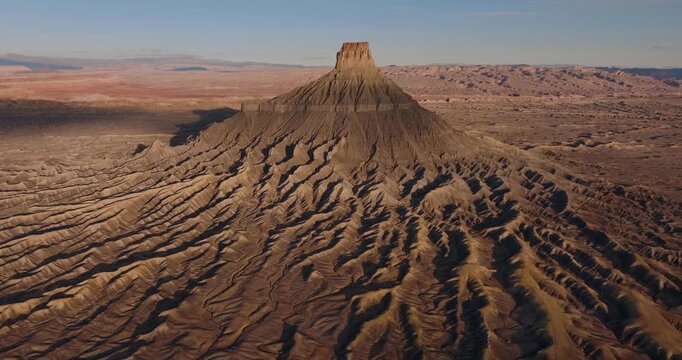 Factory Butte above dramatic desert badlands ridges in Utah arid wilderness landscape, drone