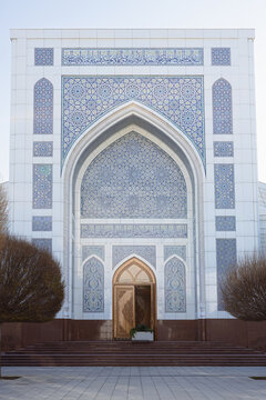 Minor mosque facade in Tashkent featuring elaborate geometric tilework and Arabic calligraphy on a grand white iwan. Ideal for travel guides, cultural publications, and architectural references.