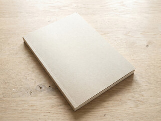 Fototapeta premium A blank book lies closed on a wooden table indoors
