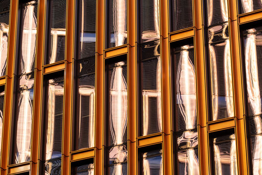 Modern architecture facade with golden glass windows and reflection forming a geometric abstract pattern in a luminous closeup detail