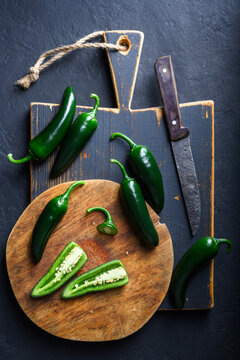 Black jalapeno with knife on rustic wooden cutting board close up. Green mexican jalapeno hot peppers