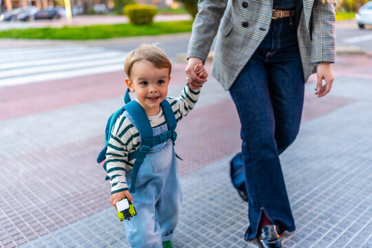 Happy toddler boy walking with parent holding hands