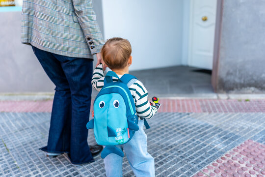Toddler holding parent's hand entering daycare