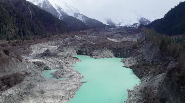 Drone view of Zhuxi glacier in Bomi County, Nyingchi, Tibet, China. High angle view of beautiful green glacial barrier lake among forest and gray rock, 4k real time footage b roll shot, travel concept