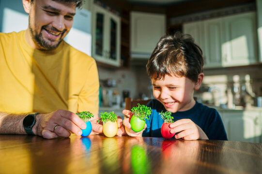 Father and son admire planted Easter egg decor in kitchen