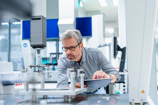 Engineer using tablet to inspect machinery in modern industrial laboratory