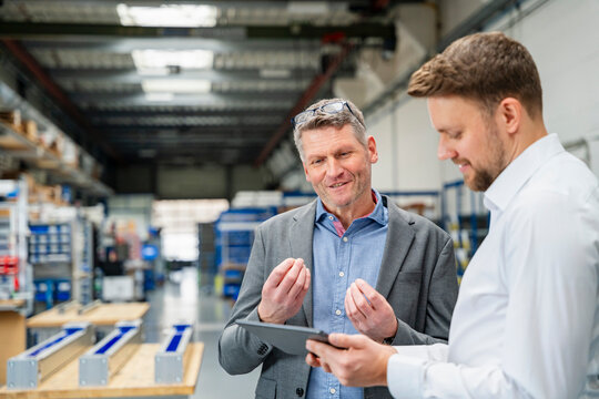 Manager and engineer discussing plans on tablet in production hall