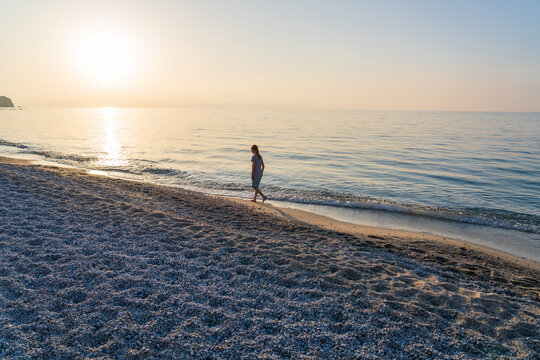 Girl walking along the sea shore at golden hour with hope and serenity