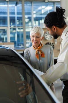 Salesperson showing car to woman in showroom