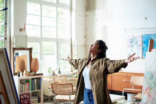 Artist standing with arms outstretched in art studio