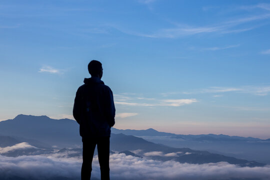 Man Standing on Mountain Overlooking Clouds
