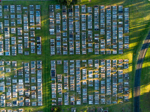 Overhead top down view of neat rows of graves in cemetery from aerial view