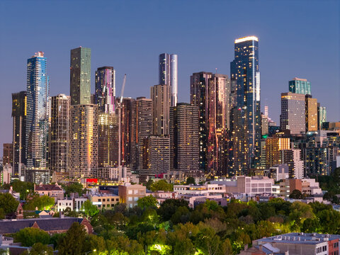 Aerial view of coloured lights on highrise buildings in a city skyline at twilight