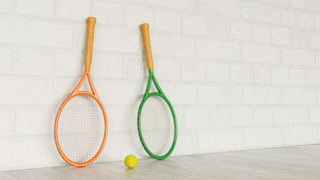 Two tennis rackets and a ball leaning against a white brick wall