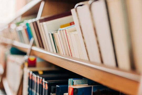 Macro of books on a wooden bookshelf in a public library