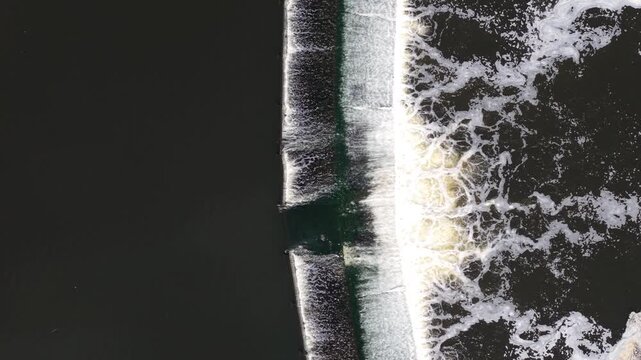 Top down aerial view of Knottingley Weir with cascading water and center fish passage notch UK