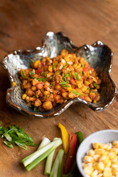 A delicious and healthy bowl of corn chaat beautifully presented on wood.