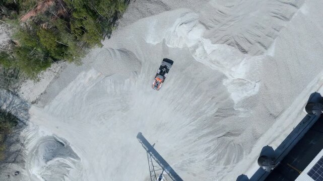 Top down aerial view of a heavy plant dumper loading raw material into a hopper in the UK