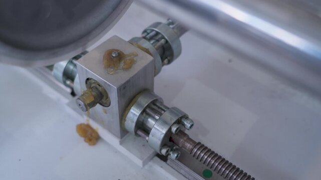 Industrial machinery lubrication, detailed close-up of a greasy aluminum gearbox.