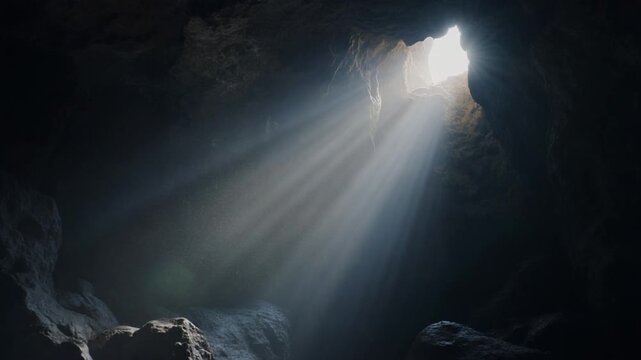 Sunbeams pierce dark cave, illuminating dust motes, ancient mystery and hope