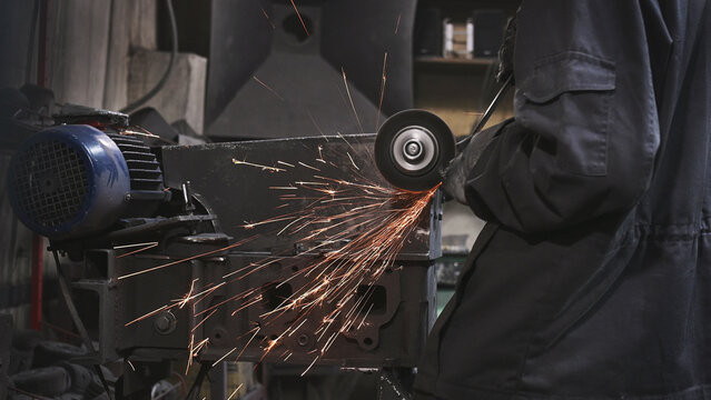 A stationary sharpening machine, grinding, sharpening, and metalworking in a garage workshop, manual work. The craftsman wears protective clothing, gloves, and goggles.