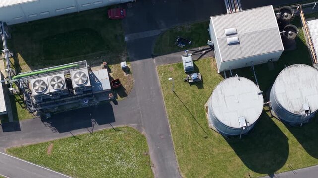 Top-down aerial view of industrial turbine cooling fans venting air from a large glass manufacturing plant in Goole, East Yorkshire, UK.