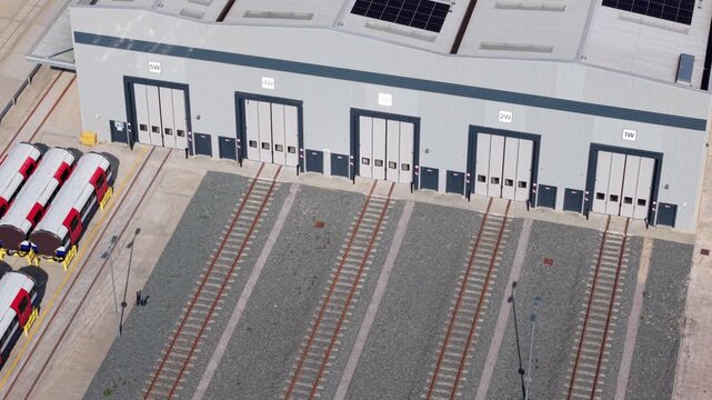 Close up aerial view of a locomotive train workyard with railways rolling into factory doors for maintenance in Goole UK