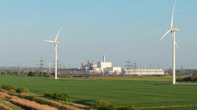 Aerial drone view of Keadby power station with a high voltage electrical substation and rural fields surrounded by wind turbines UK