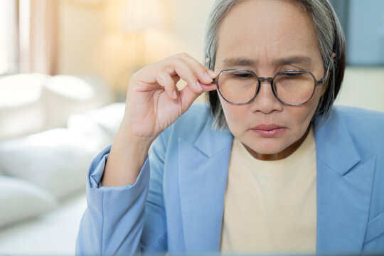 Mature woman working at desk with spectacles on head feels tired.