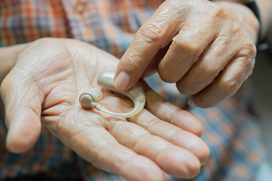 Senior patient holding a hearing aid in his hand. Medical hearing device on elder man.
