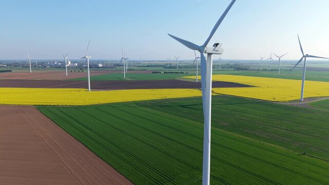 Drone view of sustainable wind generators on a flat patchwork landscape under warm evening golden light near Scunthorpe