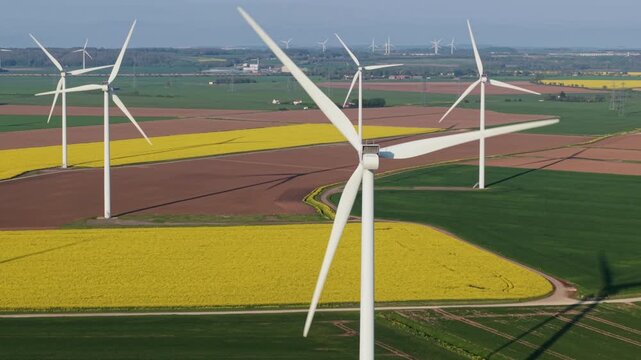 Drone view of sustainable wind generators on a flat patchwork landscape under warm evening golden light near Scunthorpe