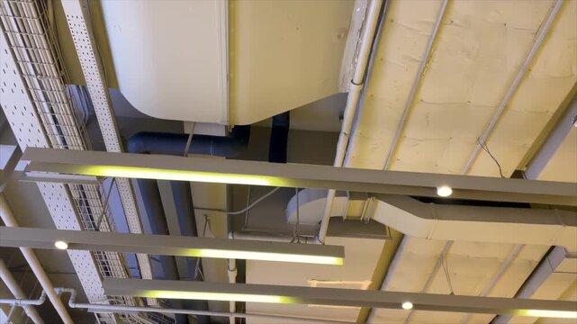 Industrial ceiling installation with pipes air ducts and modern lighting
