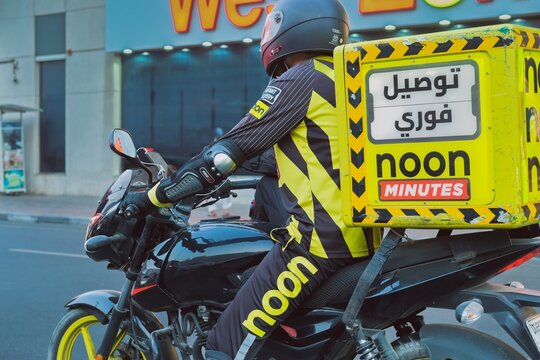 Dubai, UAE,25.10.2025: Motorcycle courier from Noon Minutes delivery service in city traffic. Concept of fast delivery, last mile logistics and on-demand economy in the Middle East.