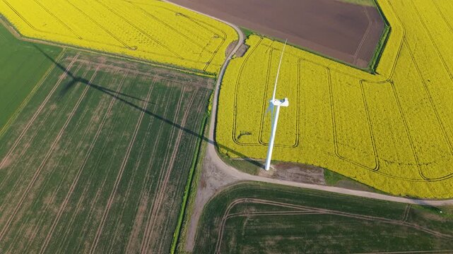 Drone shot of onshore wind turbines generating renewable energy over a multicolored patchwork of rural fields in Lincolnshire