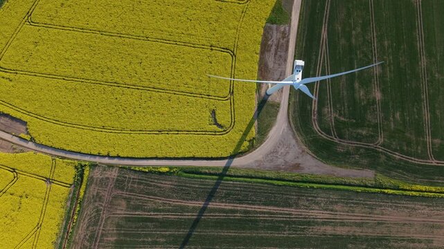Drone shot of onshore wind turbines generating renewable energy over a multicolored patchwork of rural fields in Lincolnshire