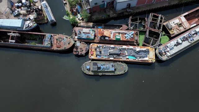 Top down aerial view of old barge boats moored near an industrial factory on the River Aire in Knottingley West Yorkshire UK