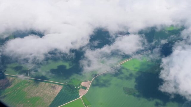 Aerial view from airplane of green meadows. White cumulus clouds. Travel, freedom concept. Aviation, transportation