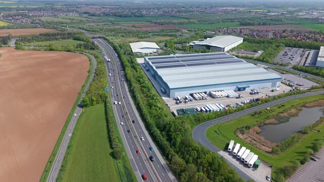 Aerial view of a large logistics distribution centre warehouse hub next to the busy A1 road with highway traffic near Doncaster, South Yorkshire, UK.