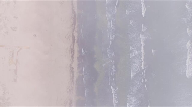 Top down view of Liepaja Baltic Sea through thin clouds with waves and sand