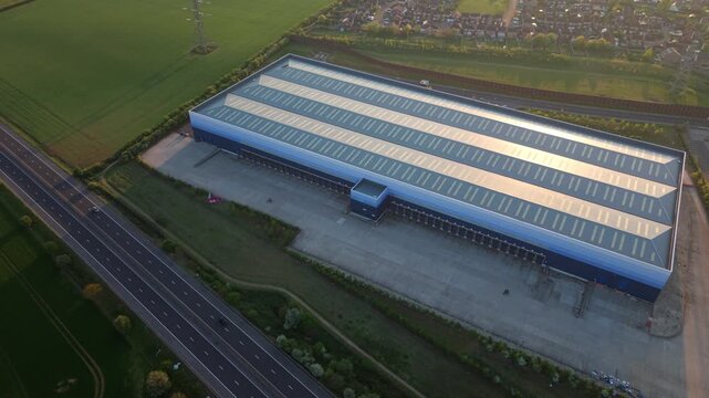 Aerial view of a huge industrial distribution warehouse complex at golden hour sunset near Doncaster, UK.