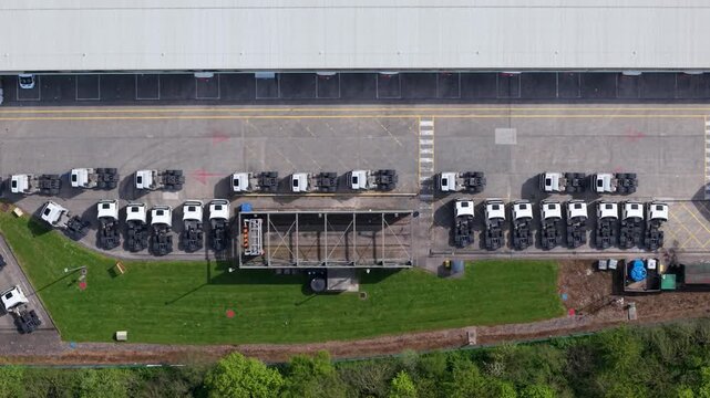 Top-down aerial view of a huge logistics warehouse facility with HGV lorries and commercial trucks in the forecourt, Doncaster, UK.
