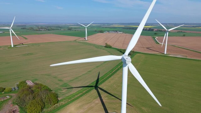 High angle aerial drone view of Keadby wind farm with rows of wind turbines generating clean electricity across colorful rural fields in North Lincolnshire England UK