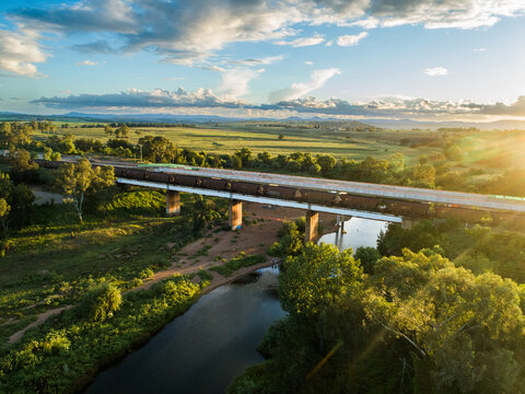 railway line with coal train at sunset crossing bridge over Hunter River
