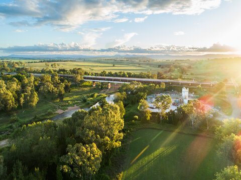 Cement plant and railway line with coal train at sunset crossing bridge over hunter river