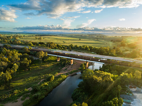 railway line with coal train at sunset crossing bridge over Hunter River