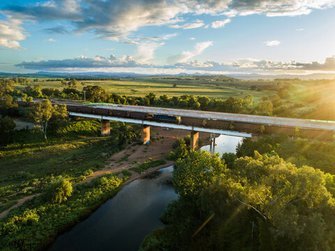 railway line with coal train at sunset crossing bridge over Hunter River
