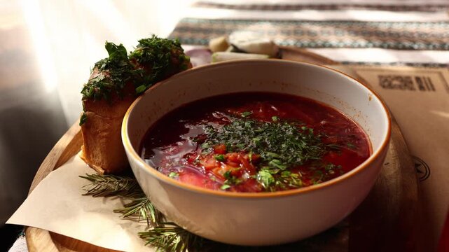 Ukrainian borscht served with fresh herbs and traditional accompaniments on a wooden board
