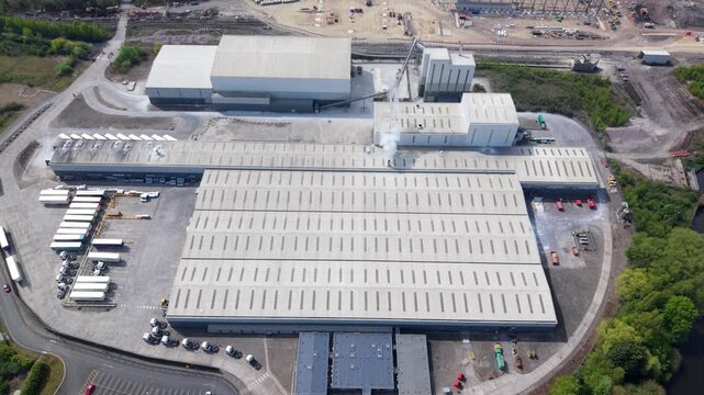 High angle aerial drone view of a large industrial factory and logistics distribution center with HGVs in loading bays in the UK